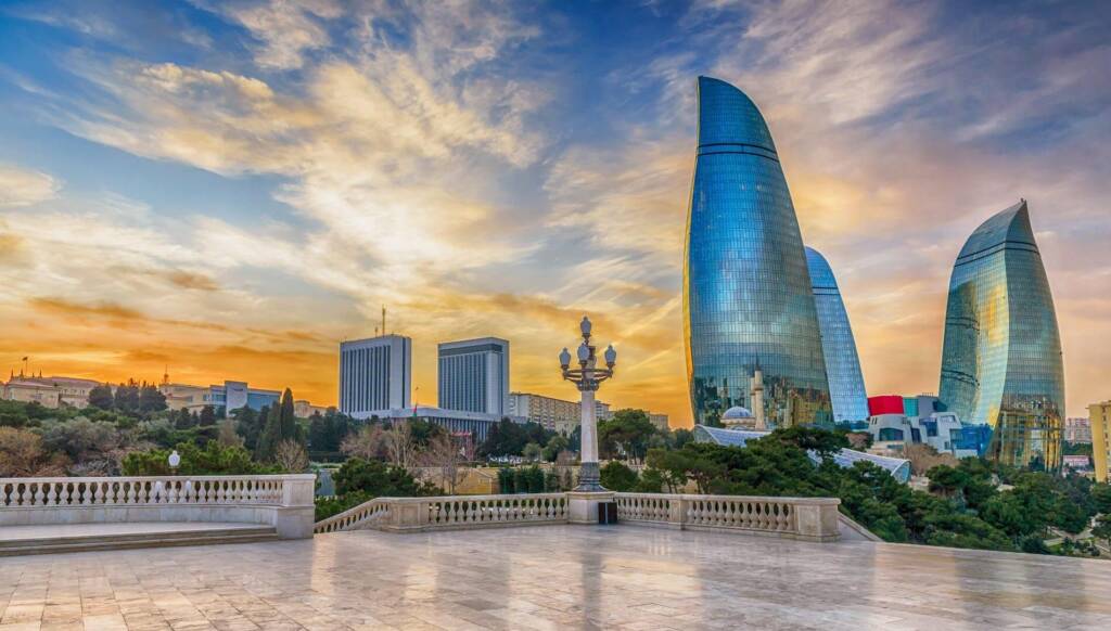 Panoramic sunset view from Highland Park (Dağüstü Park) in Baku, showing the Old City walls, the modern skyline, and the shimmering Caspian Sea extending to the horizon to do in Baku Baku travel guide 2026